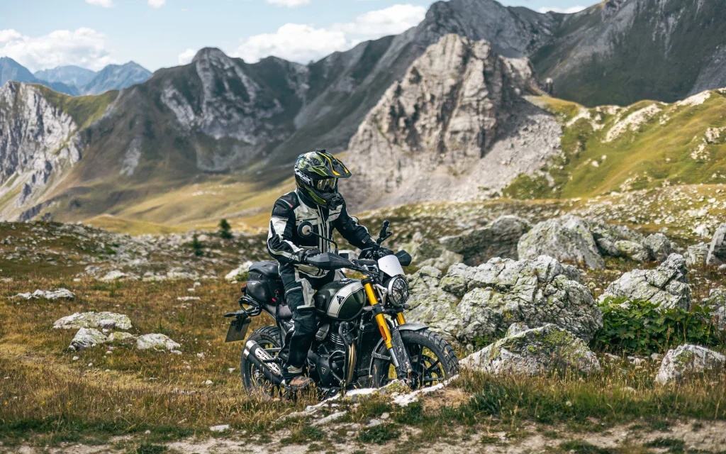 Scrambler motorcycle parked in the Swiss Alps near Furka Pass with mountain background.