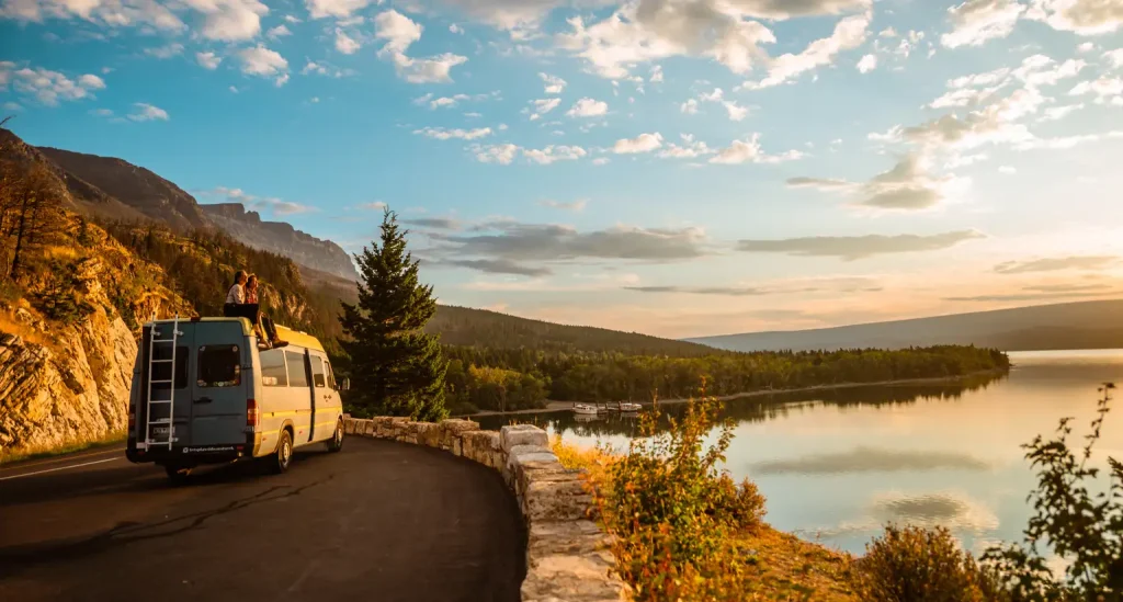 Scenic RV road trip across Europe with a camper van parked by a lake at sunset.